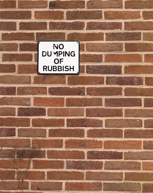 A large pile of mixed waste materials is visible on a paved driveway in an outdoor setting. The rubbish includes various items such as black plastic bags, cardboard boxes, and discarded packaging, all